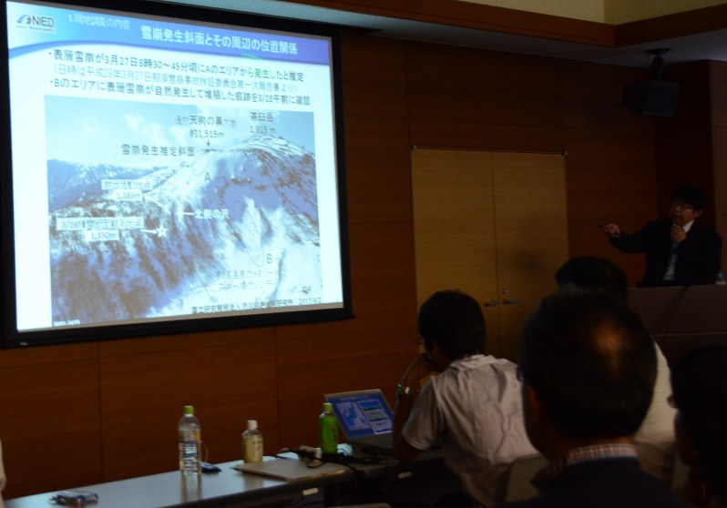 雪崩事故の現地調査結果を報告する防災科学技術研究所の中村一樹さん(右奥)=那須町で