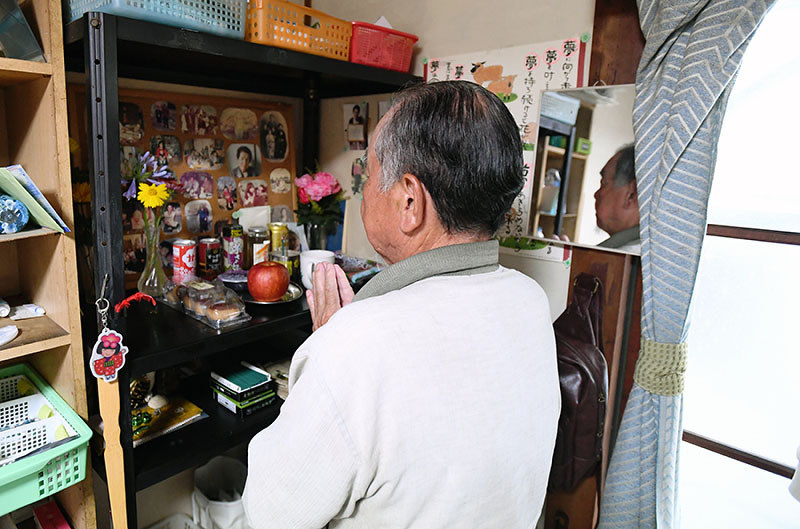 故郷の鹿児島にいる母親らを思い、写真に語りかける小田潤一郎さん=愛知県知多市で、木葉健二撮影