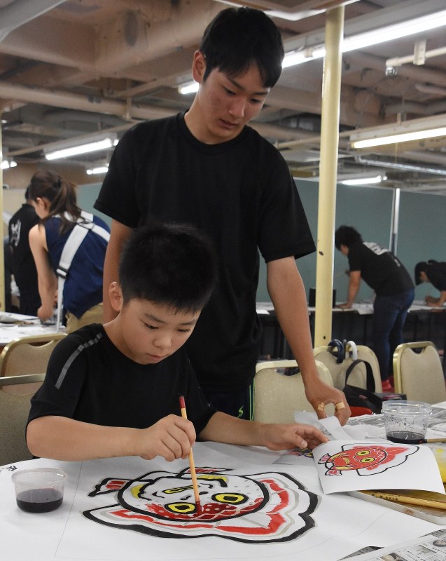 見本を参考に色つけをする参加者=青森市柳川1の青函連絡船メモリアルシップ八甲田丸で