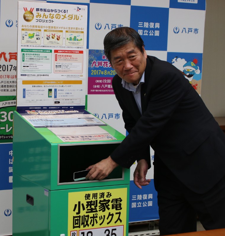 デモンストレーションで回収ボックスにスマートフォンを入れる小林真市長=八戸市役所で