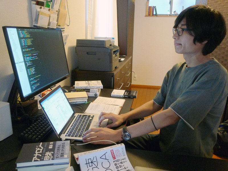 ジーニアスルーツのメンバーとチャットで情報交換しながらプログラミングの作業をする小原聖也さん