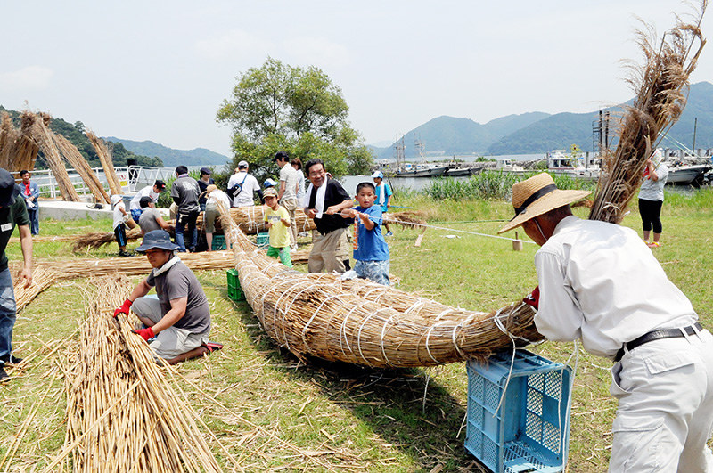 手助けする大人と共にヨシ舟作りに汗を流す子供たち=滋賀県近江八幡市の沖島で、金子裕次郎撮影