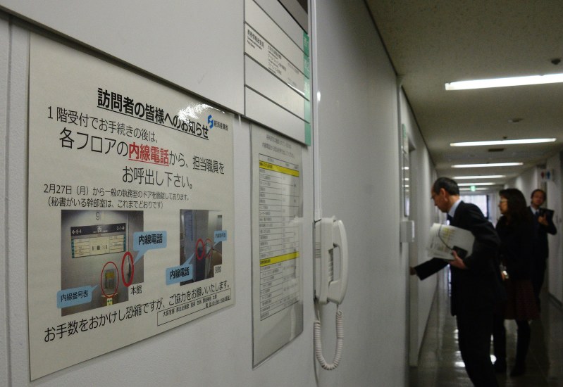 執務室のドアをカードで解錠して入室する職員ら