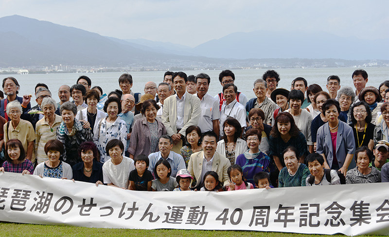 琵琶湖を背景に記念撮影する参加者=大津市のピアザ淡海近くの琵琶湖岸で、衛藤達生撮影