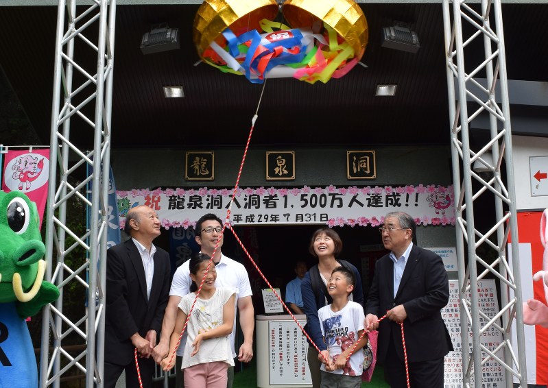 記念のくす玉を割る1500万人目の秋山修平さん親子(中央の4人)=岩泉町の龍泉洞で