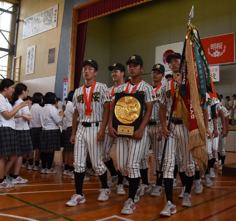 全校生徒から拍手を受け、行進する明桜の選手たち=秋田市で