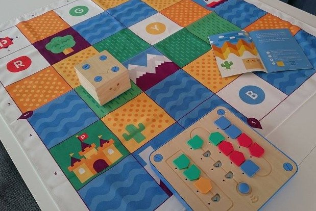 3歳からプログラミングを学べる木製玩具「キュベット」。右下のボードに動きを指示する4種のブロックを設置し、左上のロボットを動かす=稲田佳代撮影