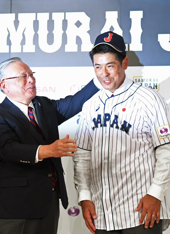 日本野球協議会の熊崎勝彦会長(プロ野球コミッショナー・左)に帽子をかぶせてもらう稲葉篤紀新監督=東京都港区で2017年7月31日午後5時48分、竹内紀臣撮影