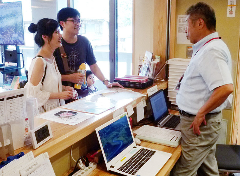 外国人観光客(左)と会話をする観光案内所のスタッフ=奈良市で、新宮達撮影