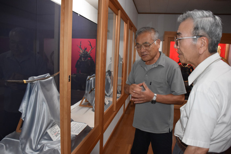 国の重要文化財の太刀「銘 友成」について説明する高照神社文化財維持保存会後援会の小嶋義憲事務局長(左)=弘前市で