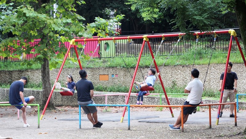 日曜日、公園で子供を遊ばせる父親たち