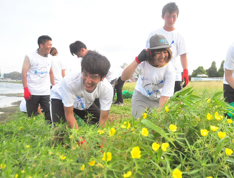 黄色い花を付けた外来植物オオバナミズキンバイを駆除する立命館大の学生たち=大津市由美浜で、大原一城撮影