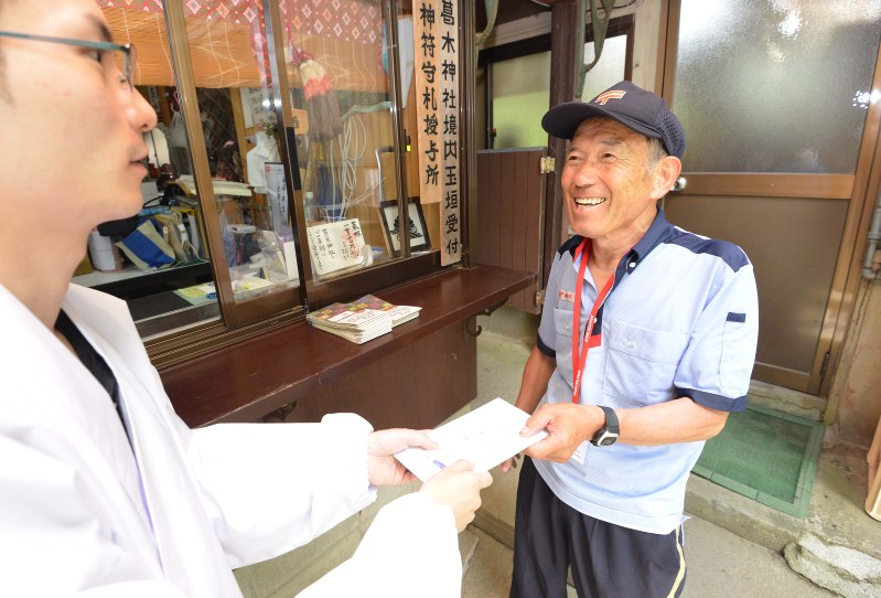 山頂にある葛木神社権祢宜(左)に郵便物を手渡す上野好夫さん=大阪府千早赤阪村で2017年7月22日、山崎一輝撮影