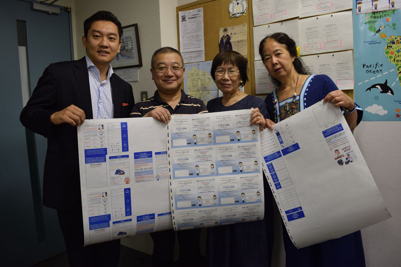 「わたしのおくすり手帳」の刷り出しを持つプロジェクトの主要メンバー=横浜市西区で