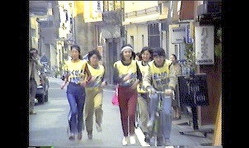 「真の男女雇用平等法を」と政府への要望書をバトンに入れ、東京都内を駅伝のように走った女性たち=映画「たたかいつづける女たち」より