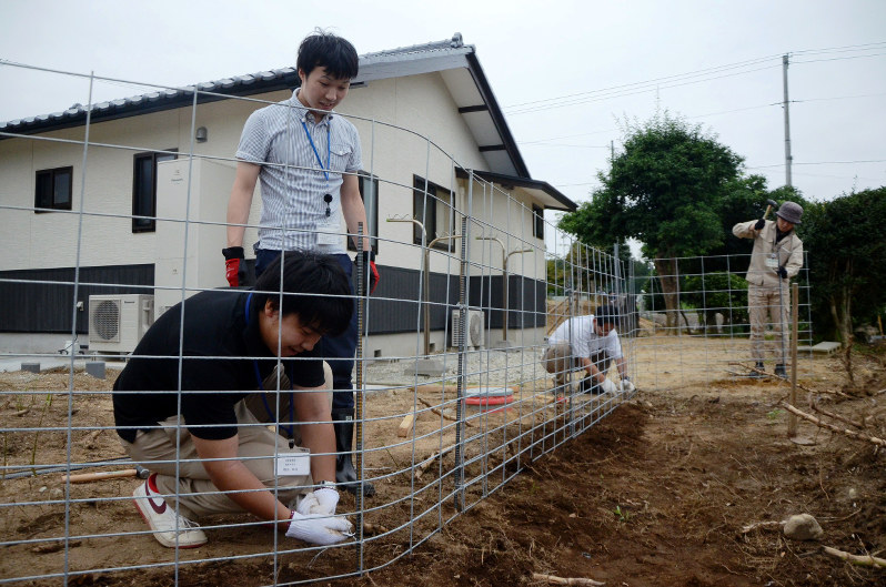 帰還住民が暮らす民家をイノシシの侵入から防ごうと、約50メートル四方の敷地を丸ごとフェンスで囲う自治体職員たち=福島県浪江町で、尾崎修二撮影