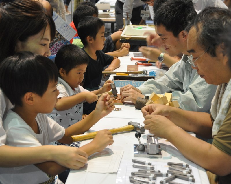 真剣な表情で職人(右)から学ぶ子供たち=静岡市駿河区のツインメッセ静岡で
