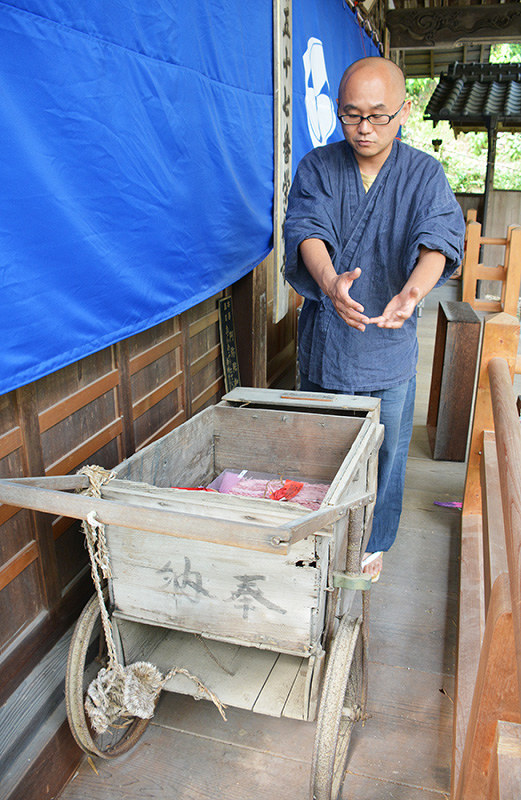 84年前に奉納されたと伝えられる箱車を示す白川密成住職。かつては足が治った人がお礼参りの際、松葉杖やギプスを箱に納めたという=愛媛県今治市玉川町八幡で、松倉展人撮影