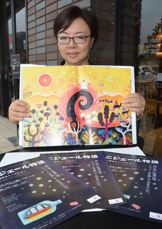 動く絵本のポスターを前に、絵本「ニジェール物語」を手にする原作者の福田英子さん=守谷市で