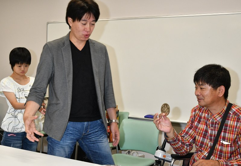 馬場さん(中央)の指導でコインマジックの練習をする大木さん(右)と香菜絵さん