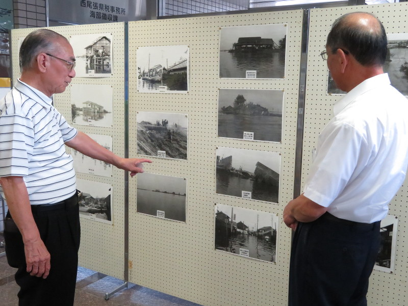 自分で撮った伊勢湾台風の被害写真の説明をする竹川英二さん(左)=津島市の県海部県民センターで