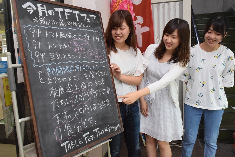 食堂に設置した案内板を前にTFTの活動を語る女子学生