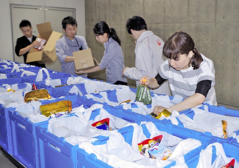 文京区役所で企業などから寄せられた食品をプラスチックケースに詰め込む、NPOのスタッフとボランティア=2日