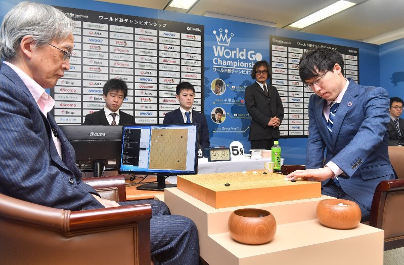 本因坊文裕(右)と対局する「DeepZenGo」。左端はZenを操作する加藤英樹さん=大阪市北区で3月23日、森園道子撮影