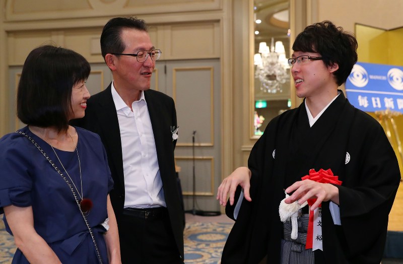 本因坊就位式・祝賀会で、母井山宏美さん(左)、父井山裕さん(中央)と談笑する本因坊文裕=東京都文京区で2017年9月29日、小川昌宏撮影