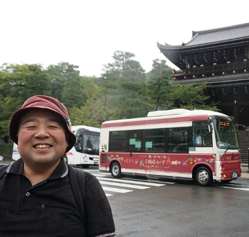 乗ってきた同じ種類の路線バスと知恩院三門とともに写真に納まる山本浩介さん。自身も乗ったバスの写真を必ず撮る=京都市東山区で9月16日、反橋希美撮影