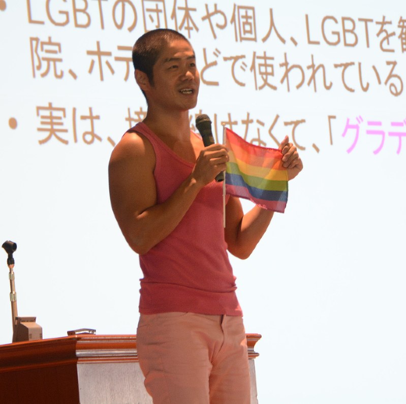 パレードでも使われるレインボーフラッグを紹介する竹内清文さん=札幌創成高校で