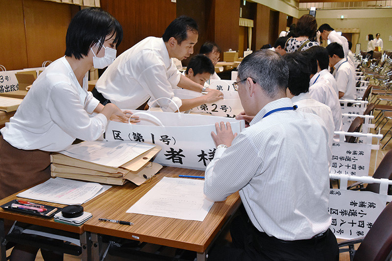 立候補者の陣営役の職員(右)を相手に選挙用の「七つ道具」を渡す手順を確認する職員ら=愛媛県庁第2別館で、成松秋穂撮影