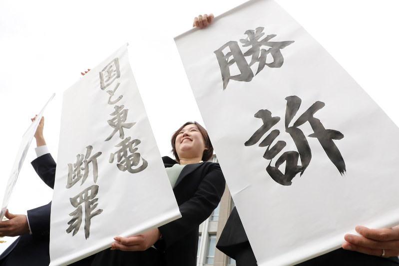 国と東電の責任が認められ、勝訴の旗を掲げる弁護士ら=福島市で2017年10月10日午後2時7分、喜屋武真之介撮影