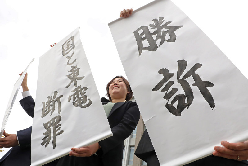 国と東電の責任が認められ、勝訴の旗を掲げる弁護士ら=福島市で2017年10月10日午後2時7分、喜屋武真之介撮影