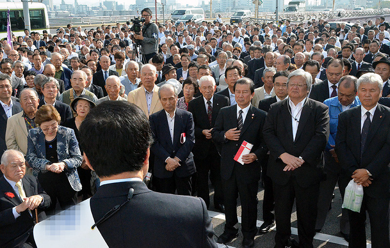 出陣式で、候補者(手前)の第一声にに聞き入る支援者ら=広島市西区で、竹下理子撮影(画像の一部を加工しています)