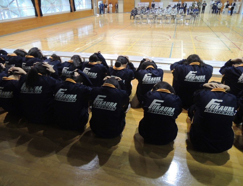 青森県深浦町の町立深浦中学校で、弾道ミサイルを想定した避難訓練に参加し、窓ガラスの飛散に備えて頭を手でかばう生徒ら=2017年10月10日、秋山信一撮影