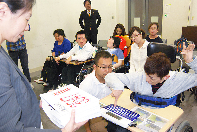 神戸市障害者支援課の三浦久美子課長(左)に署名を提出する「障がい者の声を届ける会」のメンバー=神戸市中央区で、桜井由紀治撮影