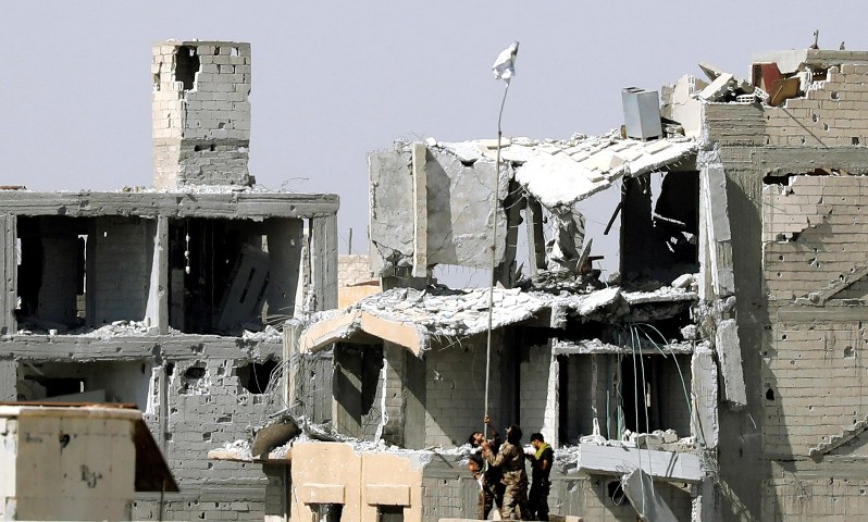 ISに実効支配されていたエリアを奪還し、旗を掲げるシリア民主軍の兵士ら=シリア北部ラッカで16日、ロイター