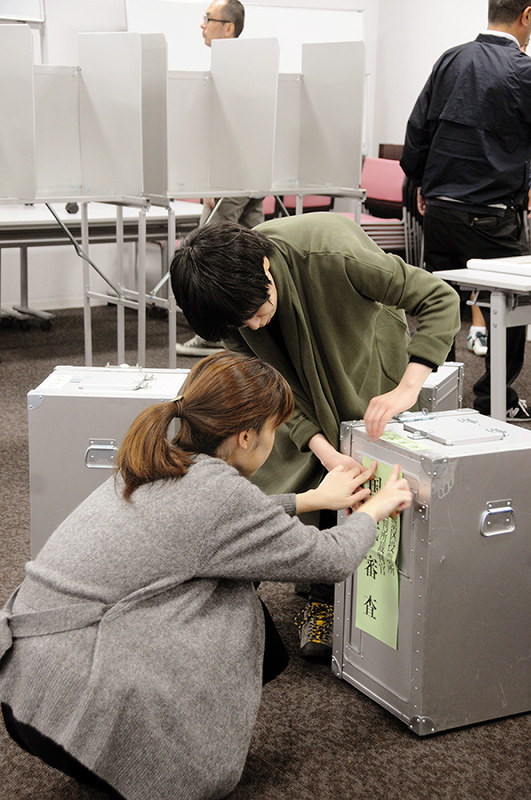 投票箱に表示の紙を貼る奈良市職員ら=奈良市三条本町のはぐくみセンターで、矢追健介撮影