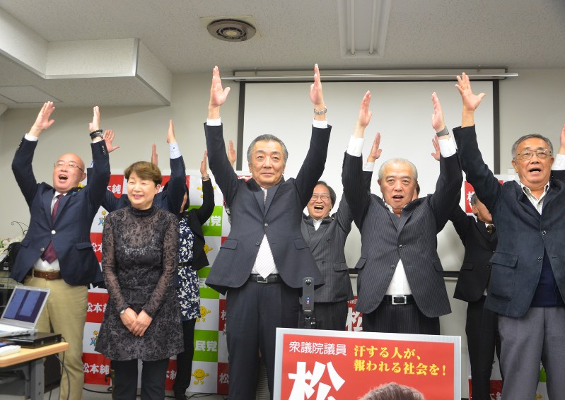 当選確実の報を受け、バンザイする松本純氏(中央)ら=横浜市磯子区で22日午後8時12分