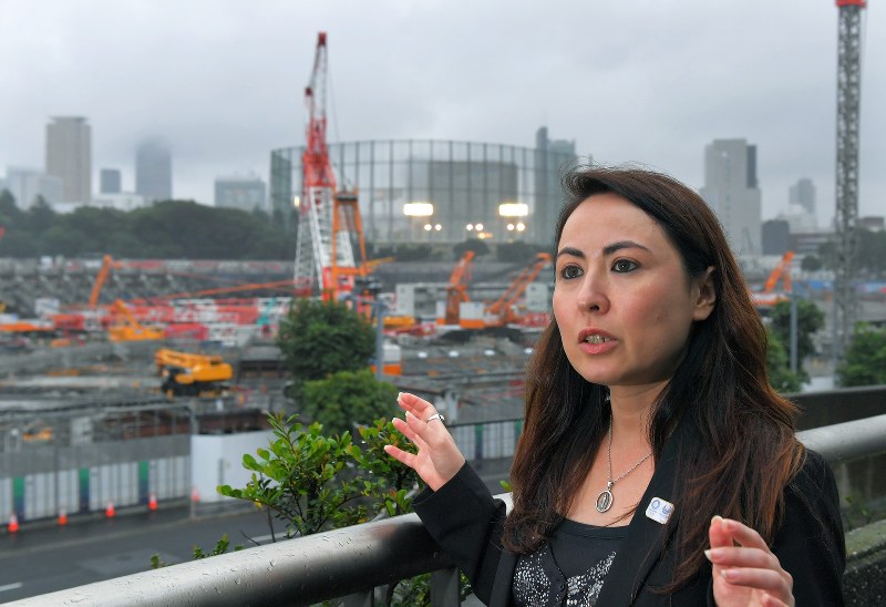 新国立競技場の建設現場を眺めながら、感想を話すリオデジャネイロ市職員の新垣ウッスィさん=東京都渋谷区で、手塚耕一郎撮影