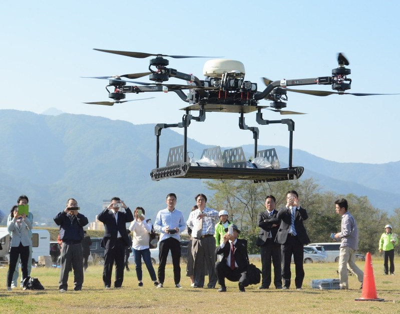 新聞を積んで上昇するドローン=山梨県韮崎市で2017年10月27日午後1時48分、滝川大貴撮影