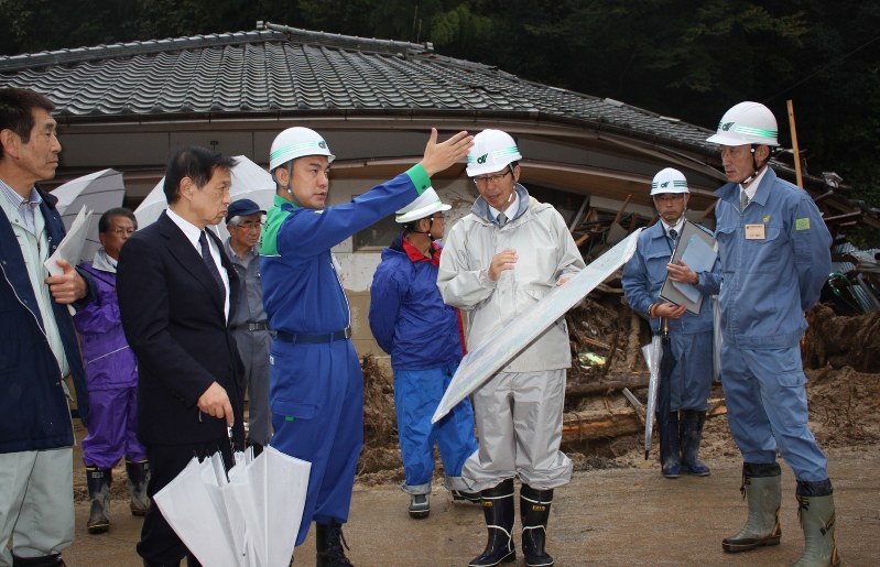 公民館が土石流でつぶされた現場で説明を受ける鈴木知事(左から3人目)と三ツ矢衆院議員(同2人目)。左端は久保町長=多気町長谷で