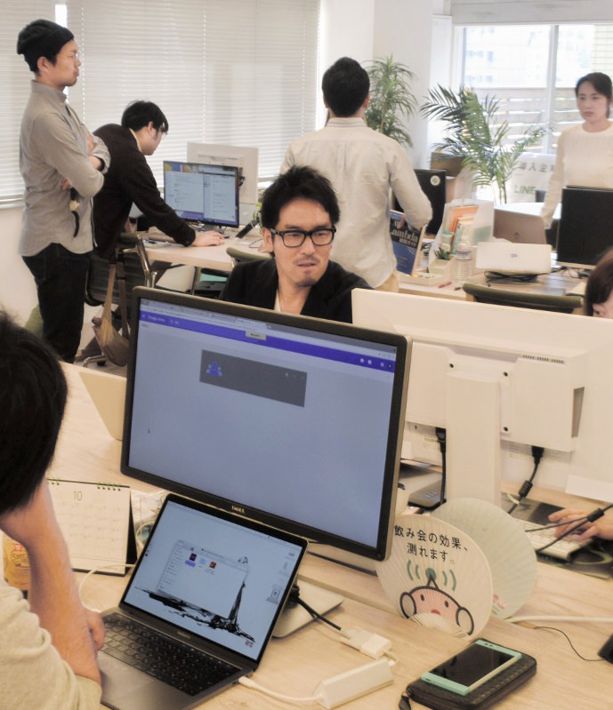 若手社員に囲まれて仕事するアトラエの新居佳英CEO(中央)=東京都港区のアトラエ本社で、鳴海崇撮影