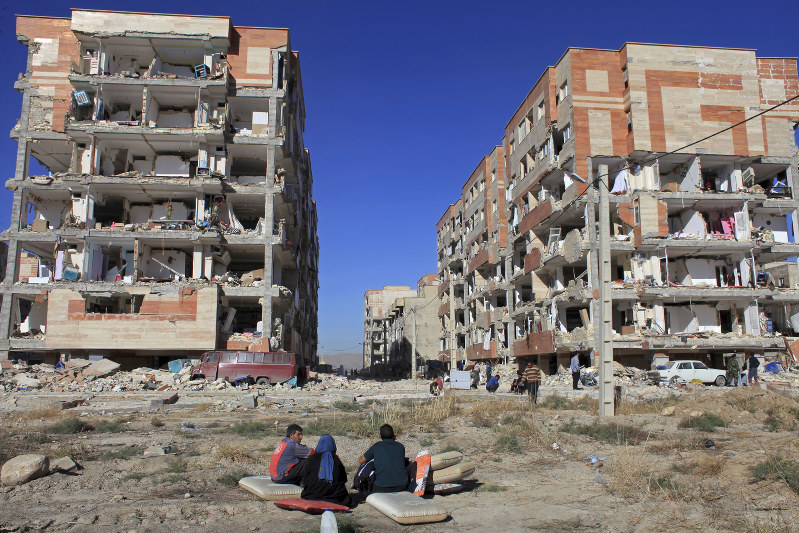 地震で損壊した建物を前に座り込む被災住民ら=イラン西部サルポレザハブで2017年11月13日、AP