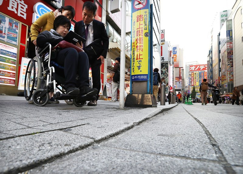 繁華街で車椅子に乗りながら歩道の段差などを調べる参加者たち=東京都千代田区で2017年11月1日、小出洋平撮影