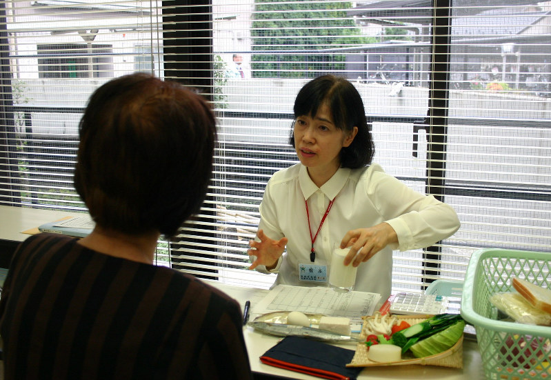 食べ物の模型を使いながら糖尿病の人(手前)に食生活の注意点を指導する栄養相談=東京都荒川区の保健所で