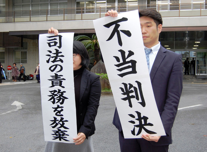 那覇地裁での1審後、不当判決の旗を掲げる原告側の弁護士=那覇市で2016年3月16日午後2時6分、川上珠実撮影