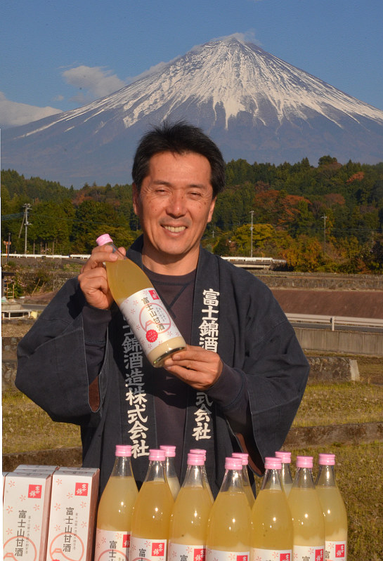 富士山を背に、甘酒をPRする清社長=富士宮市上柚野の富士錦酒造で