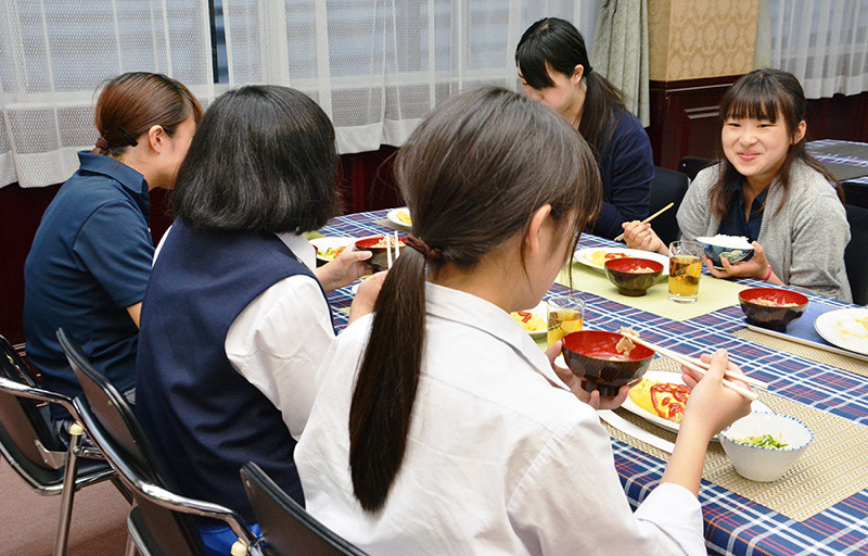 ボランティアの大学生(奥)と一緒に食卓を囲む子どもら=鳥取市で、小野まなみ撮影